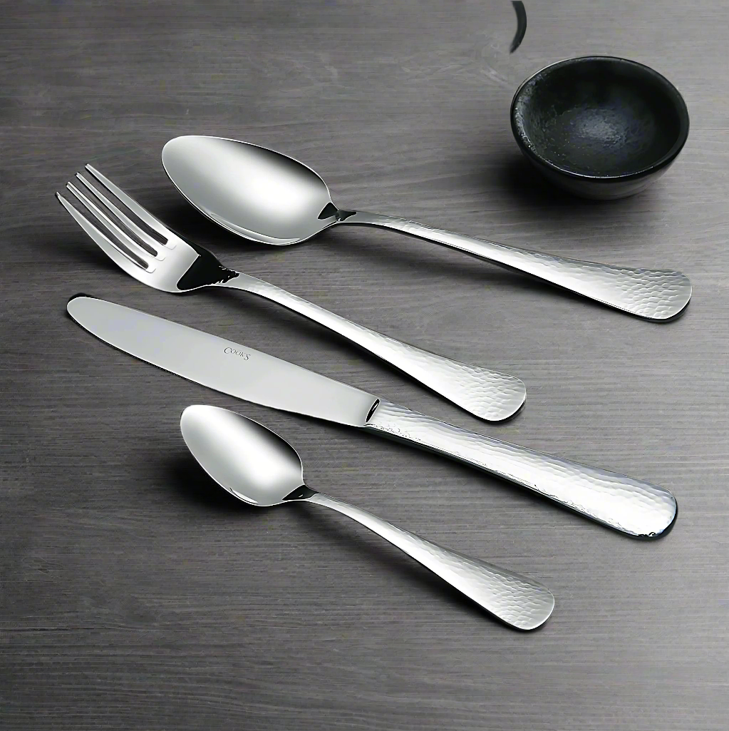 Meran Hammer cutlery set with textured stainless steel finish
Close up of Meran Hammer table knife and fork
Dessert spoon and fork Meran Hammer pattern
Tea spoon and mocca spoon with hammered texture
Table spoon and dessert knife from Meran Hammer collection
Polished stainless steel cutlery with hammered handle design
Meran Hammer flatware displayed on rustic table setting
Elegant hammered stainless steel utensils Meran Hammer